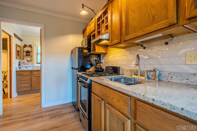 kitchen with tasteful backsplash, crown molding, light stone counters, gas range, and light hardwood / wood-style flooring