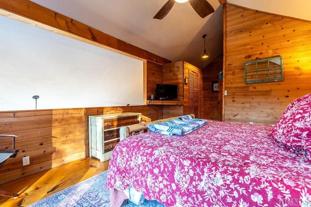 bedroom with hardwood / wood-style flooring, a closet, vaulted ceiling, and wooden walls