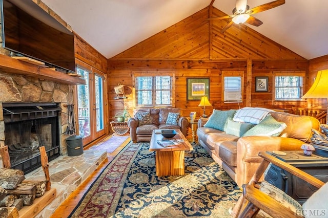 living room with ceiling fan, a healthy amount of sunlight, wooden walls, and a fireplace