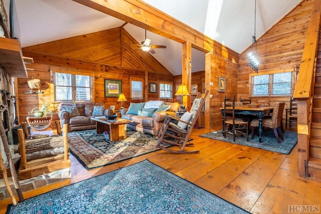 living room featuring ceiling fan, hardwood / wood-style flooring, high vaulted ceiling, wooden walls, and beam ceiling