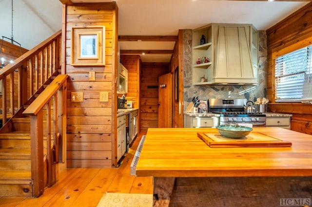 kitchen featuring light hardwood / wood-style flooring, custom exhaust hood, wood walls, butcher block countertops, and stainless steel range with gas cooktop