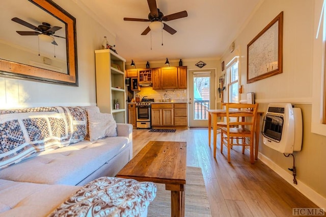 living room featuring heating unit, crown molding, light hardwood / wood-style flooring, and ceiling fan