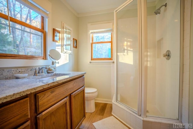 bathroom featuring toilet, an enclosed shower, hardwood / wood-style floors, and a wealth of natural light