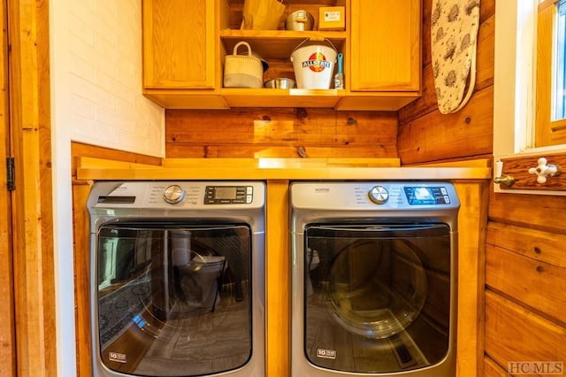 laundry area featuring separate washer and dryer, wooden walls, and cabinets