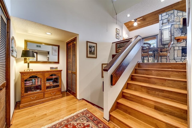 stairs with recessed lighting, visible vents, a ceiling fan, wood finished floors, and high vaulted ceiling