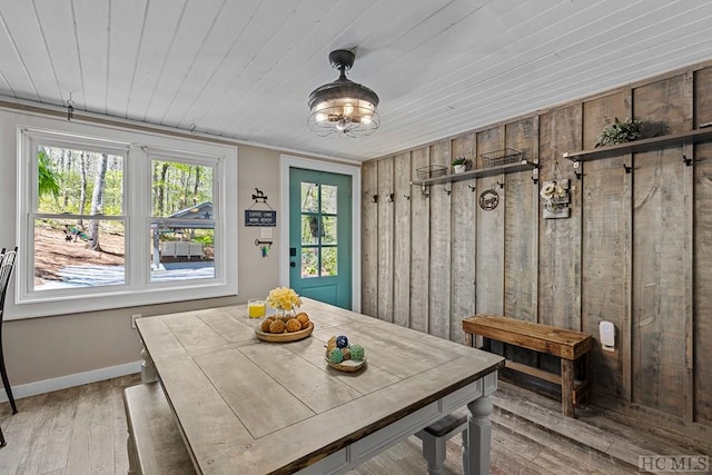 dining space with breakfast area, wooden walls, wooden ceiling, and light wood-type flooring