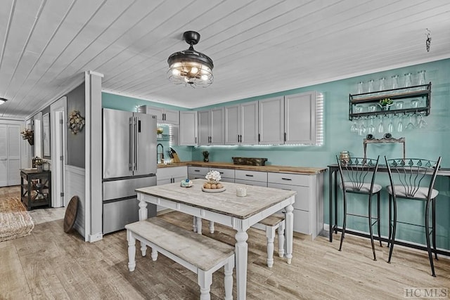 kitchen featuring sink, wood ceiling, decorative light fixtures, stainless steel fridge, and light hardwood / wood-style floors