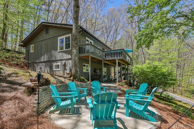 rear view of property with a patio, a deck, and a fire pit