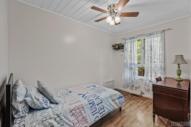 bedroom with wood-type flooring, ornamental molding, and ceiling fan