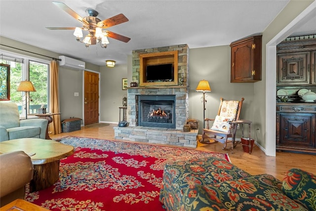 233 Strawberry Hill Rd, Cullowhee, NC 28723 - living area with an AC wall unit, a stone fireplace, light wood-style floors, a ceiling fan, and baseboards