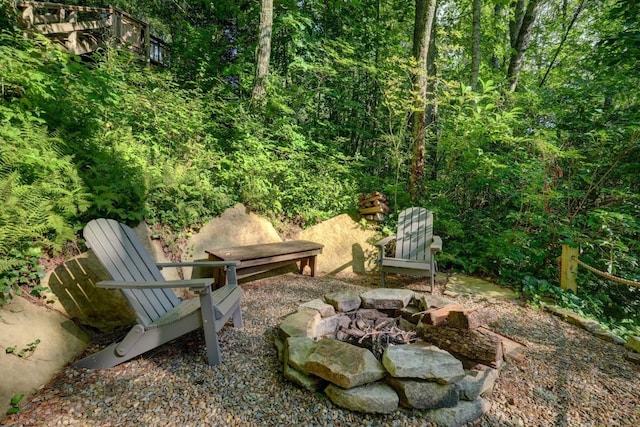 view of yard with a fire pit and a wooded view