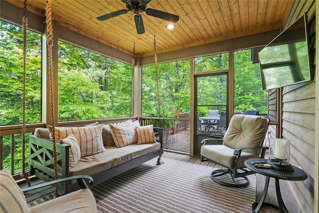 sunroom featuring a ceiling fan, wood ceiling, and a healthy amount of sunlight