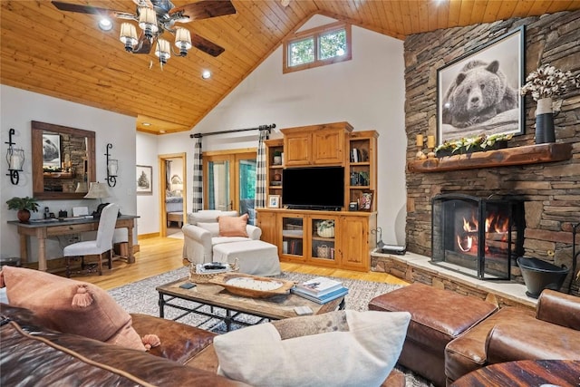 living room featuring light wood-style flooring, a ceiling fan, wood ceiling, a stone fireplace, and high vaulted ceiling