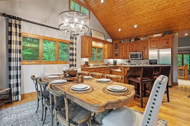 dining room with high vaulted ceiling, light wood finished floors, wood ceiling, and an inviting chandelier