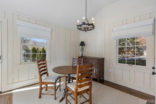 dining room featuring wood-type flooring, lofted ceiling, and a chandelier