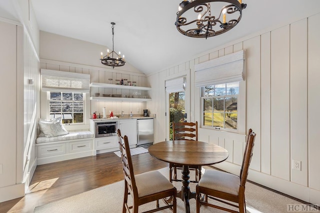 dining area featuring vaulted ceiling, dark wood-type flooring, sink, and a notable chandelier