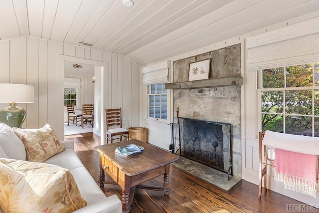 living room featuring vaulted ceiling, dark hardwood / wood-style floors, a large fireplace, and wooden walls