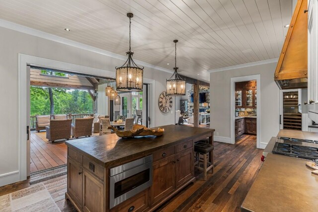 547 Burl Ln, Cashiers, NC 28717 - kitchen with stainless steel microwave, a kitchen bar, dark wood finished floors, crown molding, and a chandelier