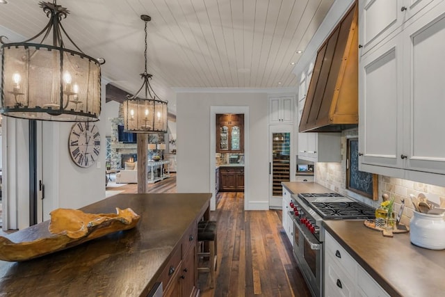 547 Burl Ln, Cashiers, NC 28717 - kitchen featuring range with two ovens, wall chimney range hood, dark wood-type flooring, decorative backsplash, and a chandelier