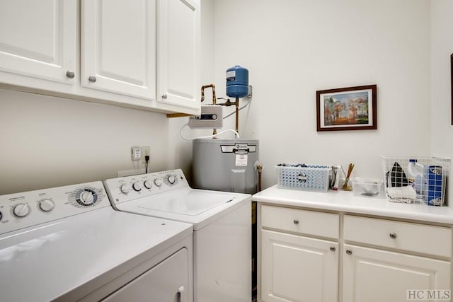 laundry area featuring washing machine and dryer, water heater, and cabinets