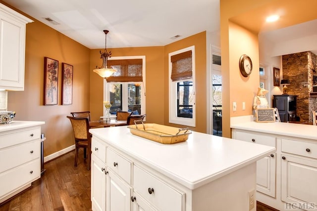 kitchen featuring white cabinetry, dark wood-type flooring, a center island, and decorative light fixtures