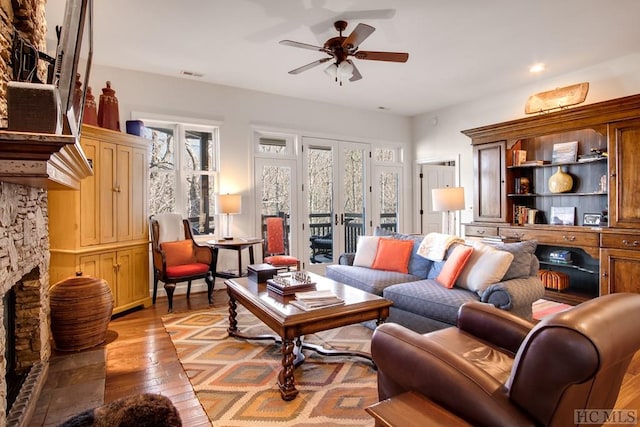 living room with a fireplace, ceiling fan, light wood-type flooring, and a wealth of natural light