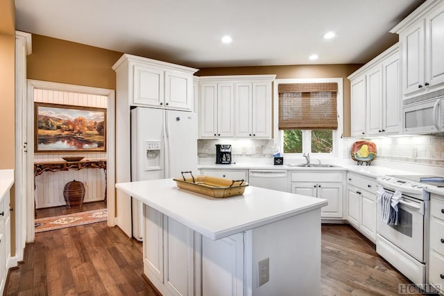 kitchen with white appliances, sink, a kitchen island, dark hardwood / wood-style floors, and white cabinets