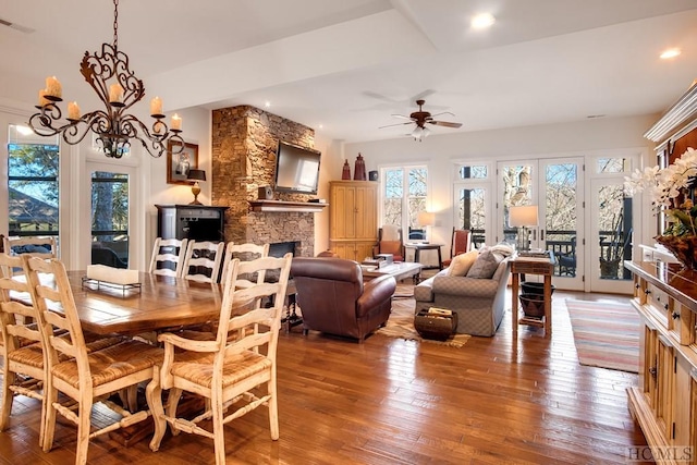 dining room featuring ceiling fan with notable chandelier, wood-type flooring, and a fireplace