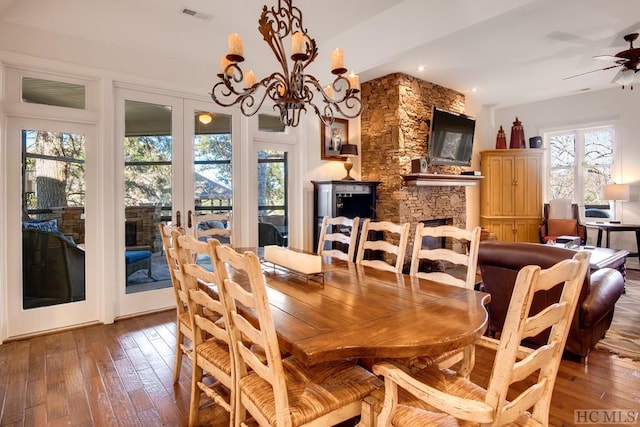 dining area with ceiling fan with notable chandelier, hardwood / wood-style flooring, french doors, and a fireplace