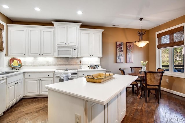 kitchen featuring white appliances, white cabinets, hanging light fixtures, and dark hardwood / wood-style flooring