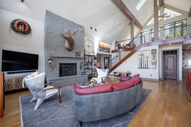 living area featuring a ceiling fan, stairway, beamed ceiling, and wood finished floors