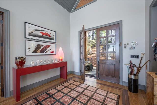 foyer with baseboards, lofted ceiling, and wood finished floors