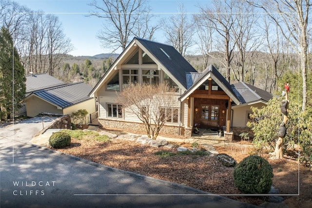 view of front of house featuring metal roof, driveway, stone siding, a mountain view, and a standing seam roof