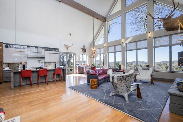 living area with light wood-style flooring and vaulted ceiling with beams