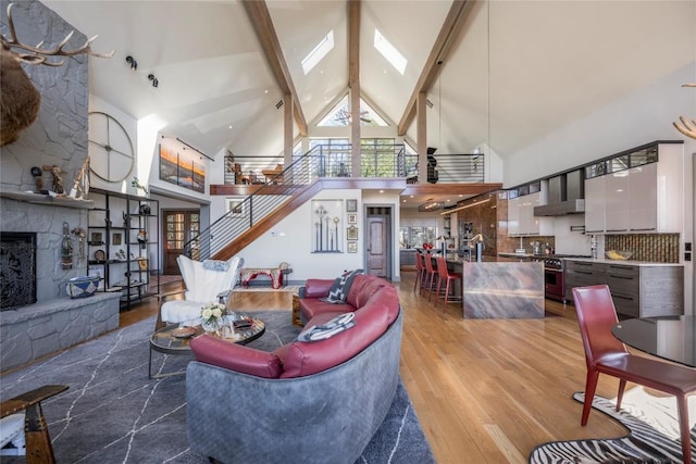 living area featuring a wealth of natural light, beam ceiling, a fireplace, and wood finished floors