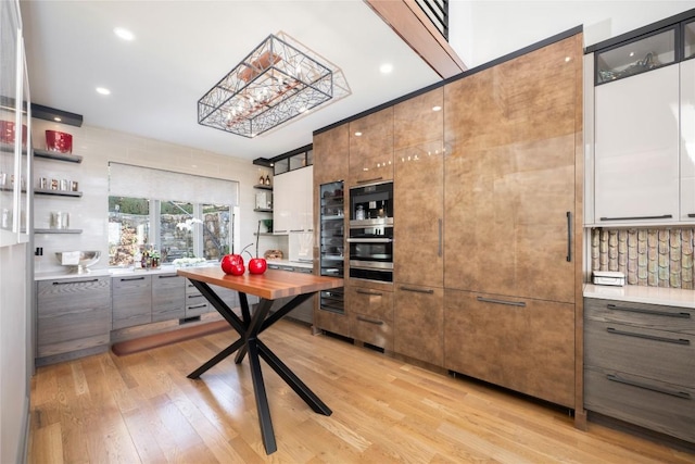 kitchen with open shelves, modern cabinets, light wood-style floors, and oven