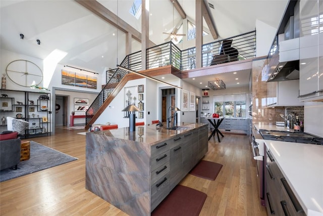 kitchen with a sink, beam ceiling, modern cabinets, and stainless steel range with gas stovetop