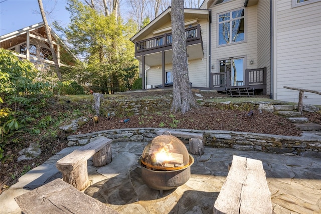 view of patio with a fire pit and a balcony