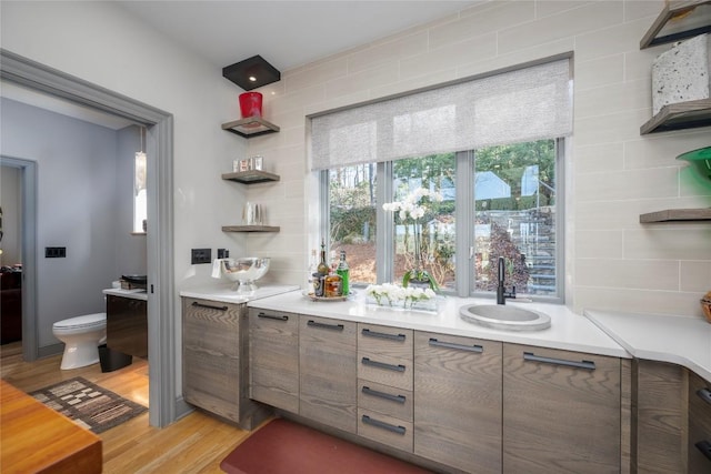 kitchen featuring a sink, open shelves, light wood-style flooring, and light countertops