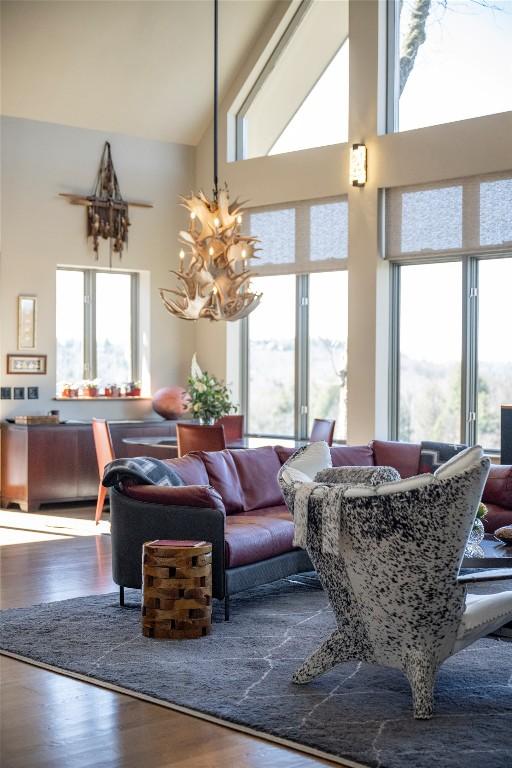 living room with a notable chandelier, wood finished floors, plenty of natural light, and high vaulted ceiling