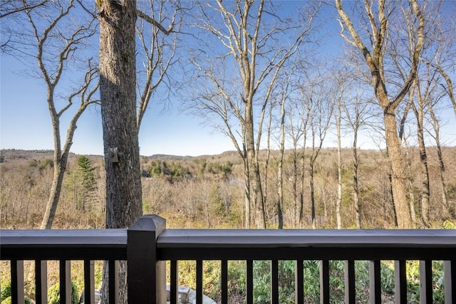 view of yard with a balcony and a wooded view