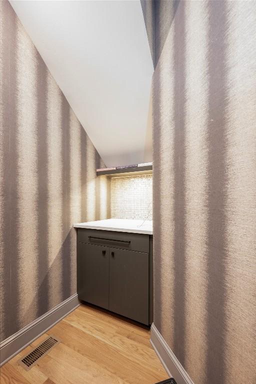 corridor featuring visible vents, light wood-style flooring, and baseboards