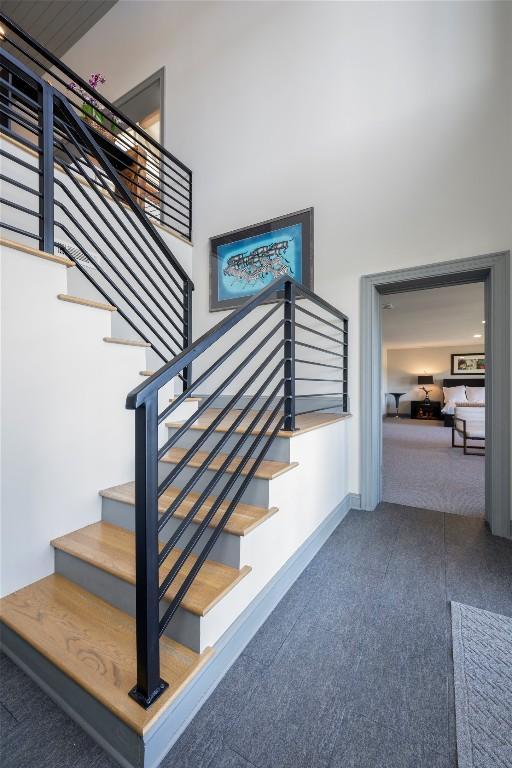 staircase with carpet, baseboards, and a towering ceiling