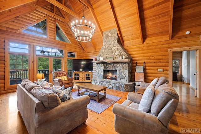 living room with a chandelier, high vaulted ceiling, beamed ceiling, a fireplace, and light hardwood / wood-style floors