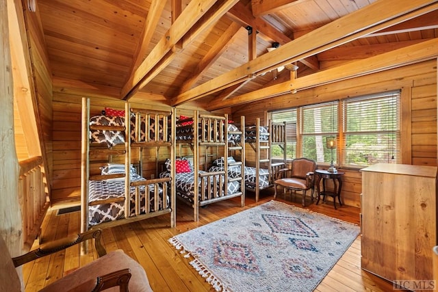 bedroom featuring vaulted ceiling with beams, hardwood / wood-style flooring, and wooden walls