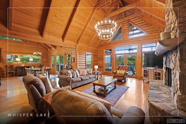 living room with a stone fireplace, beamed ceiling, a chandelier, wooden ceiling, and light hardwood / wood-style flooring