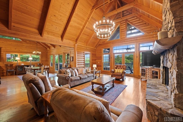 living room featuring a stone fireplace, an inviting chandelier, light wood-type flooring, wood ceiling, and beam ceiling