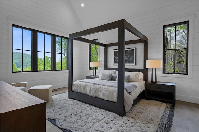 bedroom with wooden walls, recessed lighting, wood finished floors, and lofted ceiling