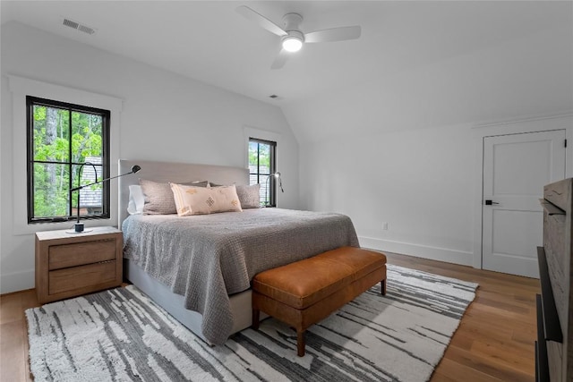 bedroom featuring ceiling fan, visible vents, vaulted ceiling, light wood-type flooring, and baseboards