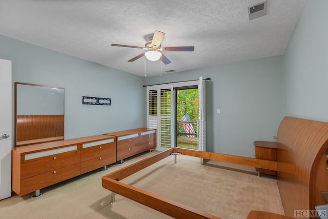 bedroom with ceiling fan, access to exterior, light carpet, and a textured ceiling